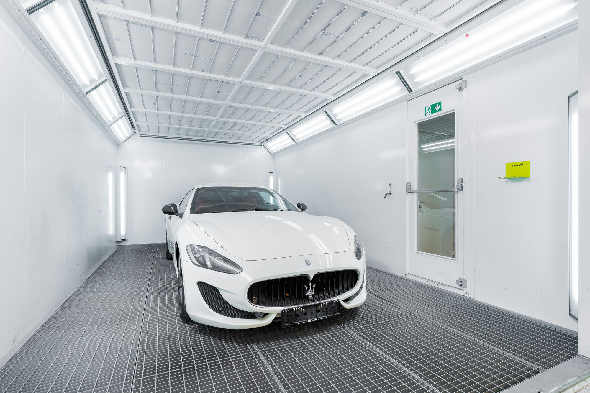 White Maserati clearly visible beneath bright paint inspection lights