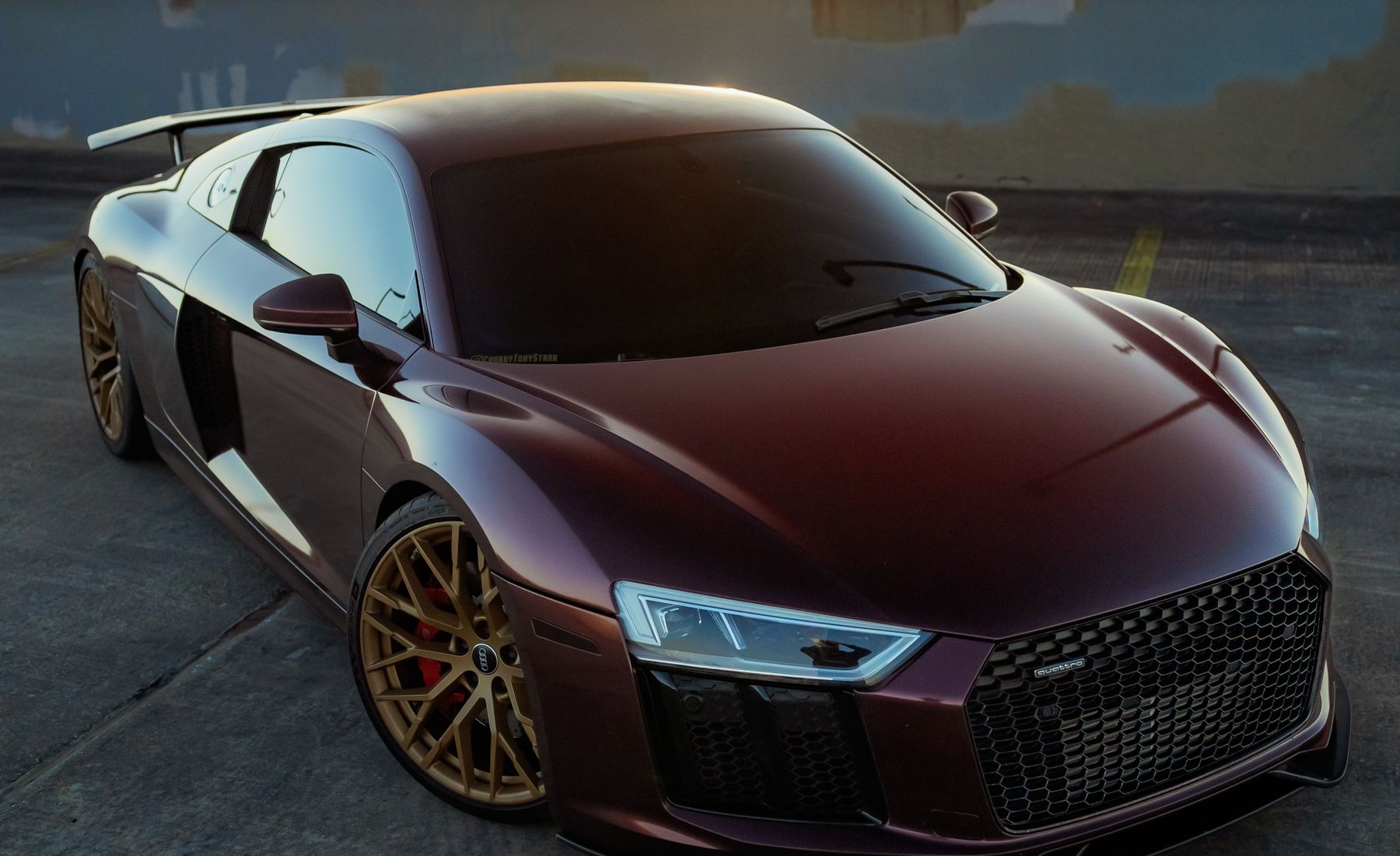 Fully visible burgundy Audi R8 with a clean reflective finish in warm evening light